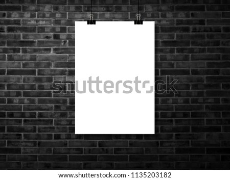 White poster Or a white frame hanging on the black brick wall background in the room.