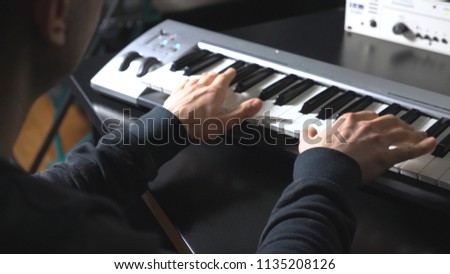 Hands of male musician playing at synthesizer. Men plays solo of music or new melody. Close up arms of pianist at the piano keys. Slow motion Rear back view.