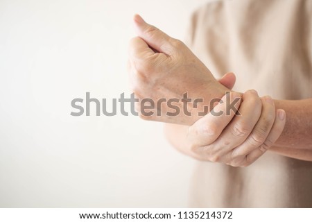 Elderly woman suffering from pain, weakness and tingling in wrist. Causes of hurt include osteoarthritis, rheumatoid arthritis, gout or wrist sprain. Health care concept. Copy space.