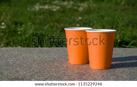 A selective focus picture of an craft paper cups in green leaf garden