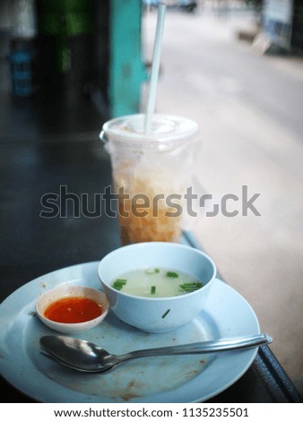 empty dish after finishing typical popular fast food THAI lunch menu with soft drink in clear plastic glass authentic shot on pathway footpath in BANGKOK city selective focus blur background