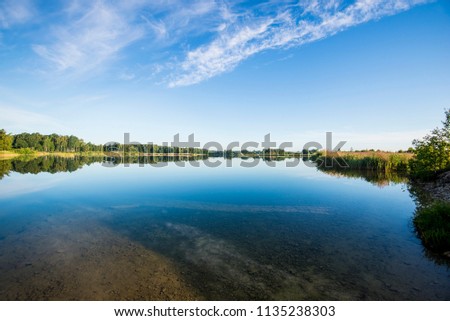 Panoramic view of the blue lake with a forest in the background, Latvia
