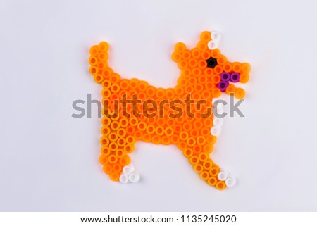 Orange perler bead dog. Close up. White isolated background.