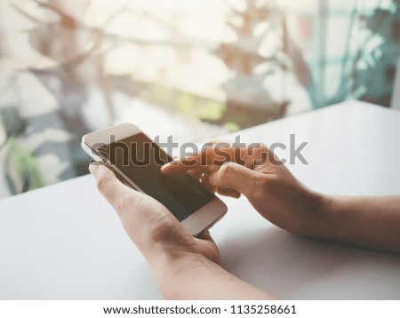 Mockup image of woman hand holding and touching white mobile phone with blank screen black colour smartphone