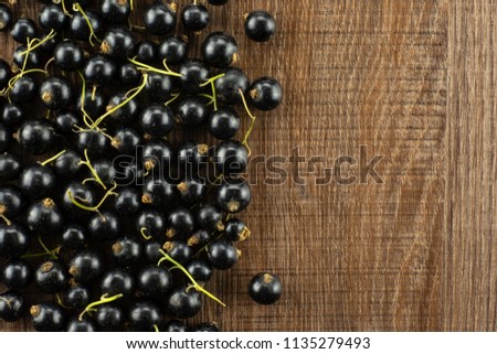Lot of whole fresh black currant berry ben gairn variety left corner flatlay on brown wood