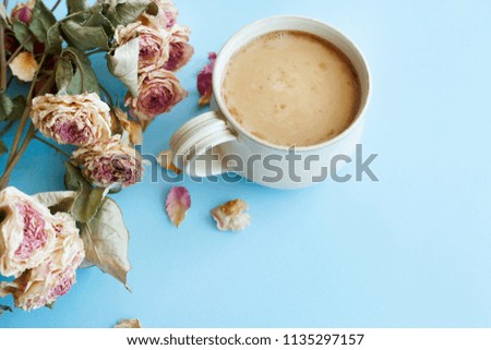 Picture of autumn background with dry roses and cup of coffee with copy space over blue background