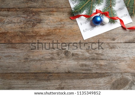Flat lay composition with Christmas decorations and music sheet on wooden background