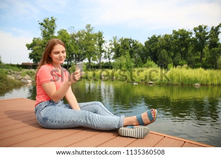 Young woman taking selfie on wooden  bridge near river