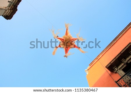 Pink Mexican Piñata suspended in the Street with Blue Sky and Orange Building Royalty-Free Stock Photo #1135380467