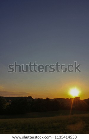 sunset in south germany allgau evening with trees on horizon and green grass meadow landscape