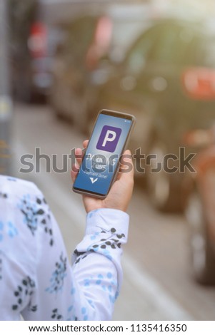 Woman using smartphone app to pay for parking in the paid parking zone in a city