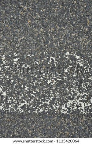 A worn white reflective road marking close-up on an asphalt pavement