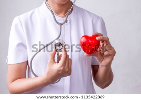Nurse holds a stethoscope, medical equipment for checking heart rate, and red heart model to show method to examine cardiovascular system Royalty-Free Stock Photo #1135422869