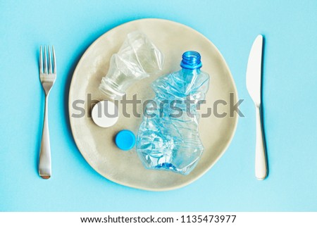 plastic pollution of food concept, handmade plate with plastic bottles and caps on blue background Royalty-Free Stock Photo #1135473977