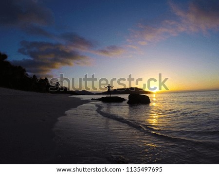 Travel / vacation / holiday summer concept. View of the sunset on the sea and the white sand tropical beach with palm trees silhouettes, Boats/yachts on the water. Beautiful exotic background.
