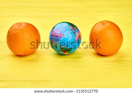 Globe and oranges on colorful background. Fresh organic fruits and globe on light wooden background.