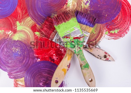 Three 2 inch paintbrushes stacked with red purple green wet paint swirl pattern