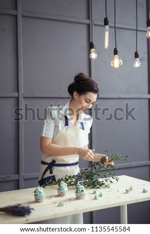 confectioner in a white apron on a dark background with a cupcake