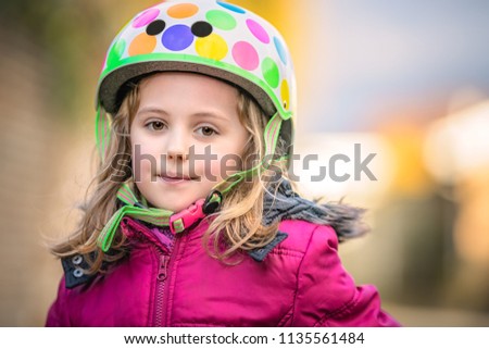 Portrait of a young Caucasian little girl wearing small colorful cycling helmet