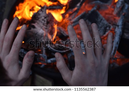 Man warming up his hands on the fire
