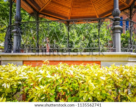 A beautiful bandstand with a wooden brown roof and a geometrical shape is the famous Chamberi square in Madrid the capittal of Spain, in Europe. The picture was taken in Summer, in a sunny morning.