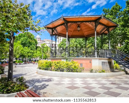 A beautiful bandstand with a wooden brown roof and a geometrical shape is the famous Chamberi square in Madrid the capittal of Spain, in Europe. The picture was taken in Summer, in a sunny morning.