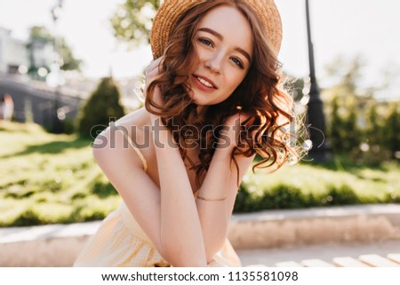 Debonair caucasian girl with ginger hair posing in park. Jocund red-haired young woman spending summer weekend outdoor.