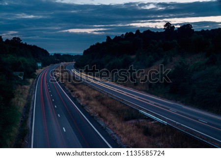 Night traffic on England’s motorways, with motion blurred light tracks glowing, right after sunset. Concept of traffic, transportation, travel, road safety, transport industry. Royalty-Free Stock Photo #1135585724