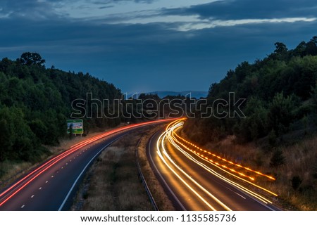 Night traffic on England’s motorways, with motion blurred light tracks glowing, right after sunset. Concept of traffic, transportation, travel, road safety, transport industry. Royalty-Free Stock Photo #1135585736