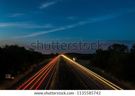 Night traffic on England’s motorways, with motion blurred light tracks glowing, right after sunset. Concept of traffic, transportation, travel, road safety, transport industry. Royalty-Free Stock Photo #1135585742