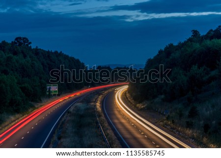 Night traffic on England’s motorways, with motion blurred light tracks glowing, right after sunset. Concept of traffic, transportation, travel, road safety, transport industry. Royalty-Free Stock Photo #1135585745
