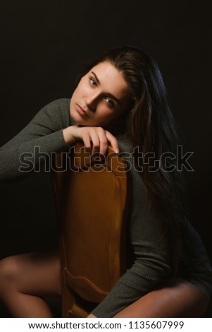 Sad brunette woman sitting in studio during model tests, dressed in grey underwear and jeans shorts
