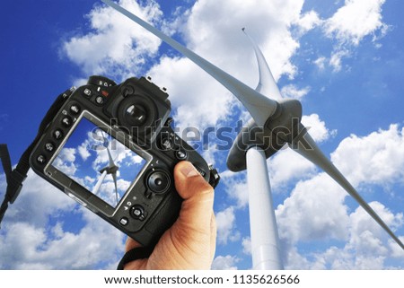 Freelancer photographer with DSLR camera taking picture of wind turbine in a sunny day
                      