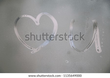 inscription love you on window. handwritten sign and heart