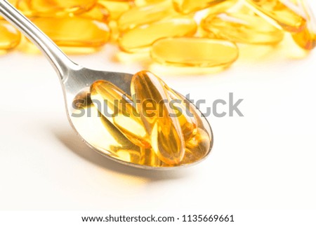fish oil capsules in a spoon on white background