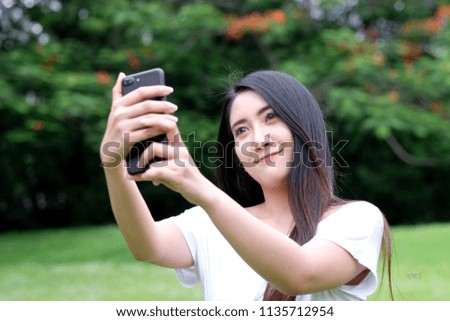 Young asian woman using smartphone to selfie her portrait at nature park background, poeple and technology, lifestyle, travel blogger