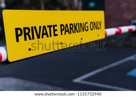 Yellow colored sign PRIVATE PARKING ONLY on the parking barrier at the entrance of car park.