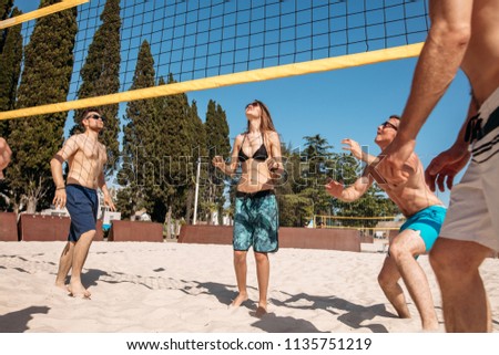 Vacationer active male and female players doing summer sports trying to block a dangerous attack in a beach volleyball game