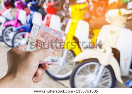 Man holding money have a picture of a motorcycle as a background.