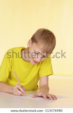 Cheerful boy in a yellow T-shirt has a good time at home