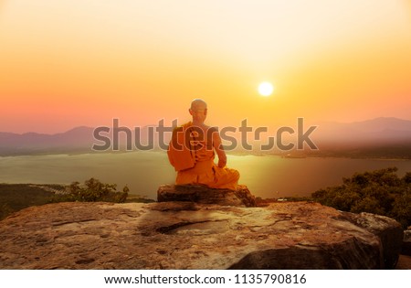 Buddhist monk in meditation at beautiful sunset or sunrise background on high mountain Royalty-Free Stock Photo #1135790816