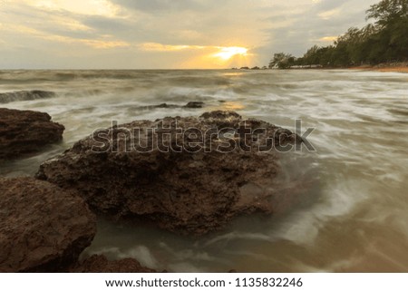sunset at sea with rock on the beach
