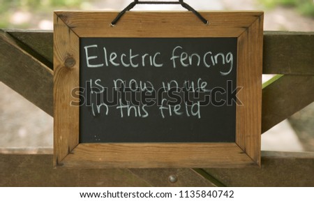 "Electric Fencing is Now in this Field" Sign Attached to a Wooden gate on a farm in Rural Somerset, England, UK