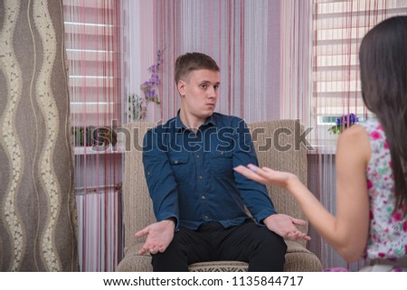 family relations, problems, difficulties, the dispute of young husband and wife on the sofa in the bedroom. The husband and wife are sitting right in front of the camera and look unhappy