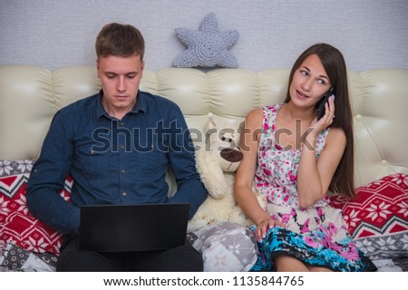 family relationships, the problems of a young husband with a laptop and his wife in the bedroom. The husband and wife are sitting right in front of the camera and look unhappy