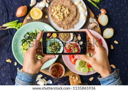 Smartphone food photography of vegetarian lunch or dinner. Woman hands taking phone photo of food in trendy style for social media or blogging. Royalty-Free Stock Photo #1135865936