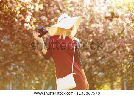 Beautiful girl in summer hat holding camera