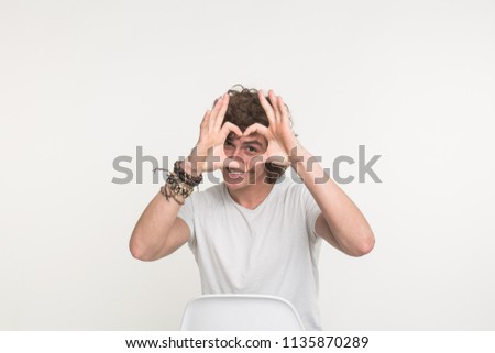 Portrait of happy handsome young man making heart with fingers on white background