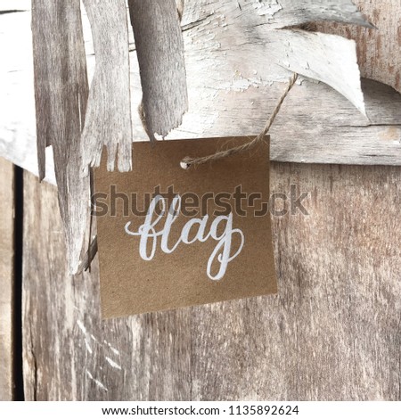 Flag hand-lettered on a brown art paper with white paint hanging on a old wooden 