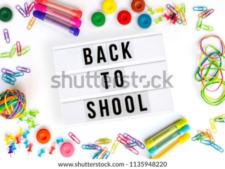 Back to school written in a light box, colorful school supplies isolated on white